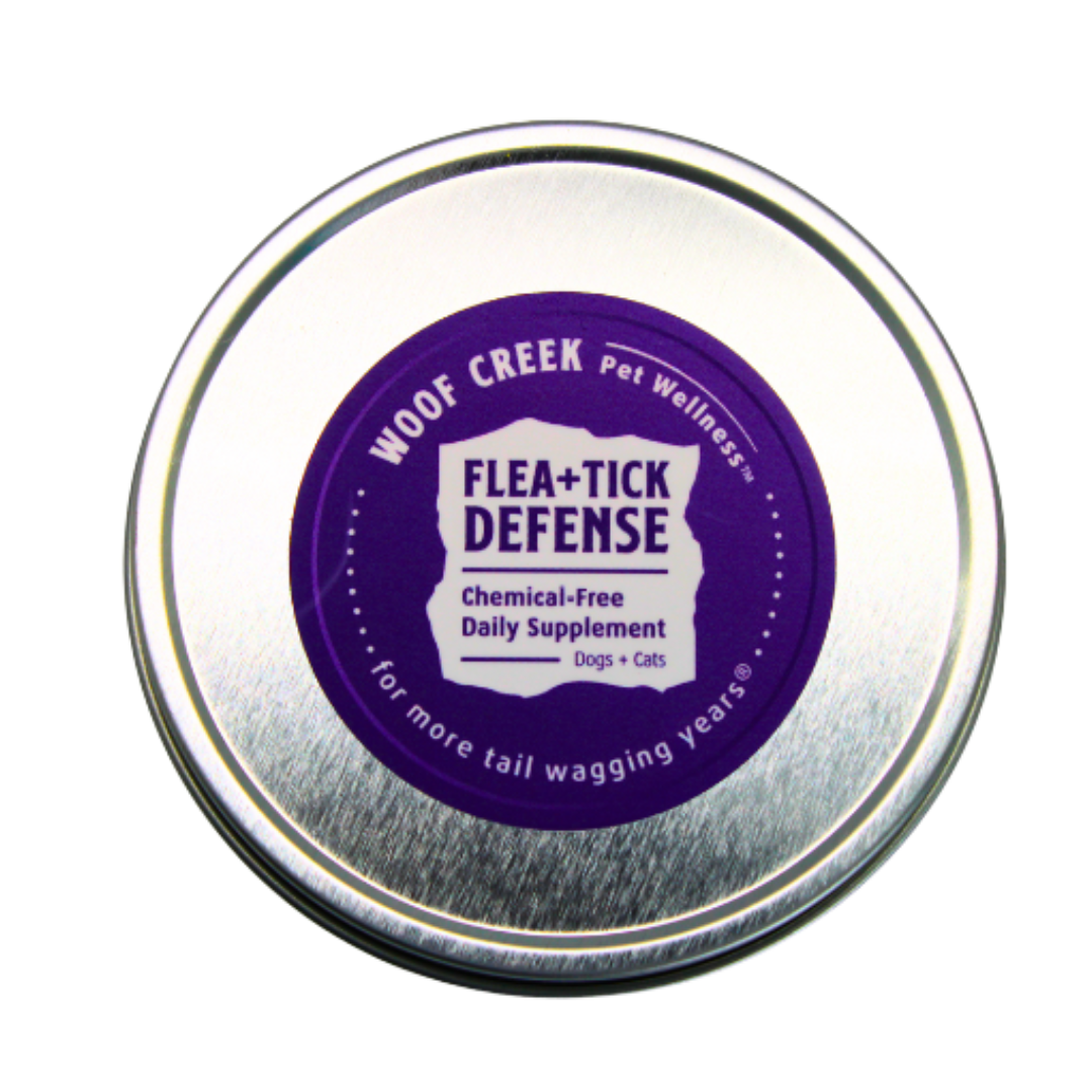 Woof Creek Pet Wellness Flea + Tick Defense supplement tin on a white background