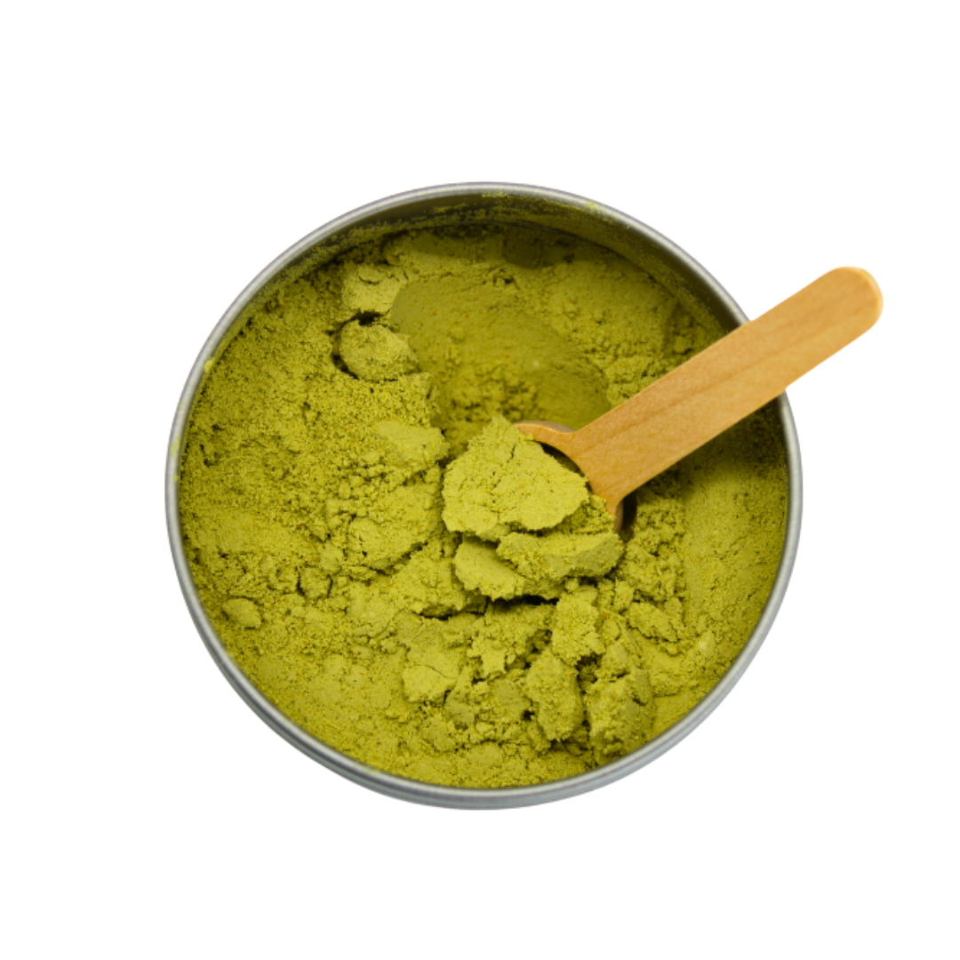 Green powder in a metal container with a wooden scoop on a white background