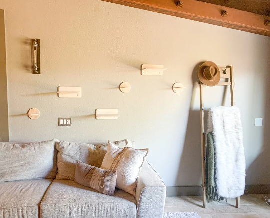 Living room with a beige sofa, decorative pillows, and wall lights along with cat wall ledges in natural wood.