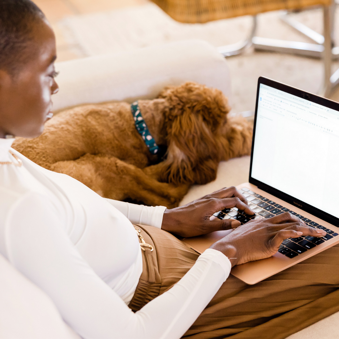 girl on laptop sitting next to her dog