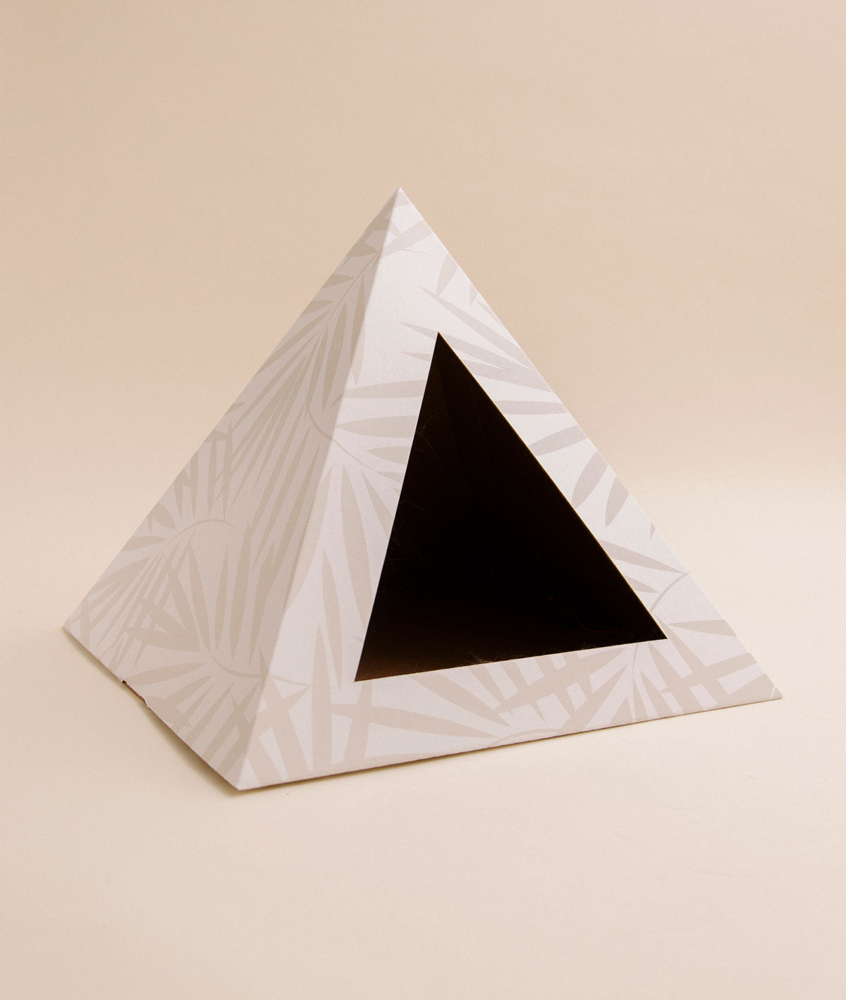 Triangular cat bed with geometric pattern on a beige background