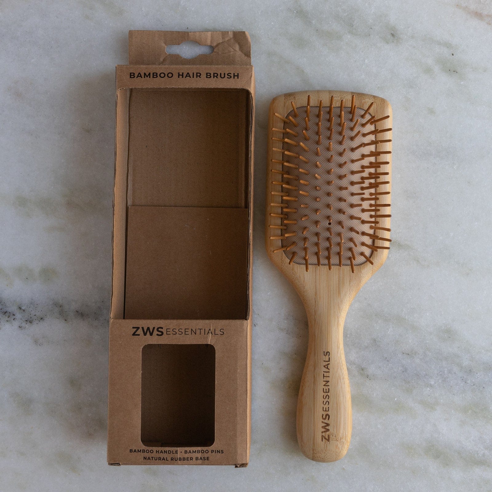 Bamboo hair brush with packaging on a marble surface