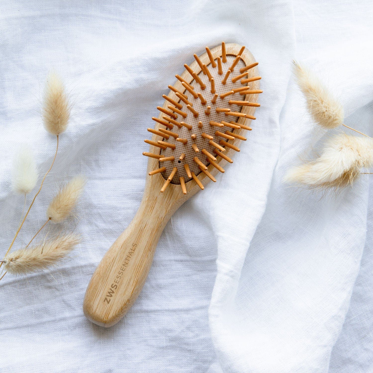 Wooden hairbrush with bristle head on a light fabric background