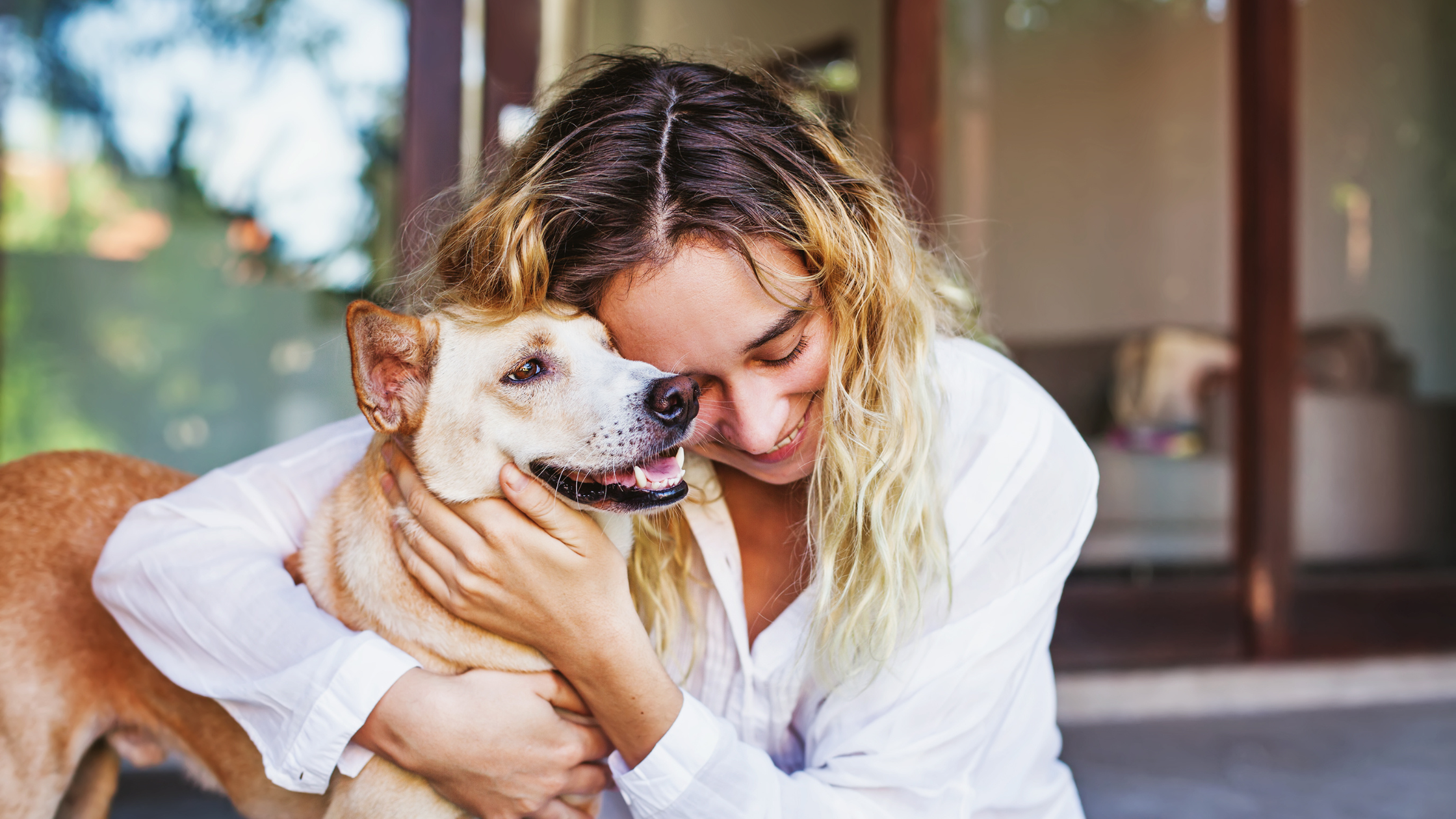 woman in white shirt hugging her dog