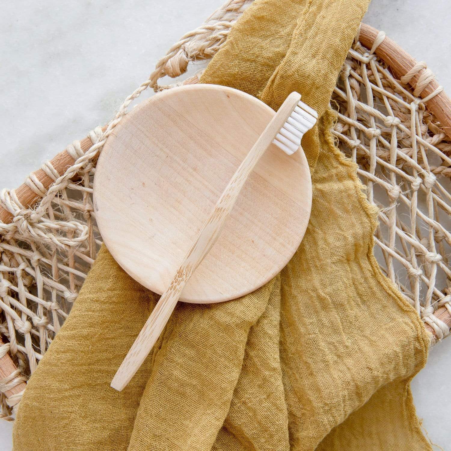 Wooden toothbrush and holder on a yellow cloth with a textured background