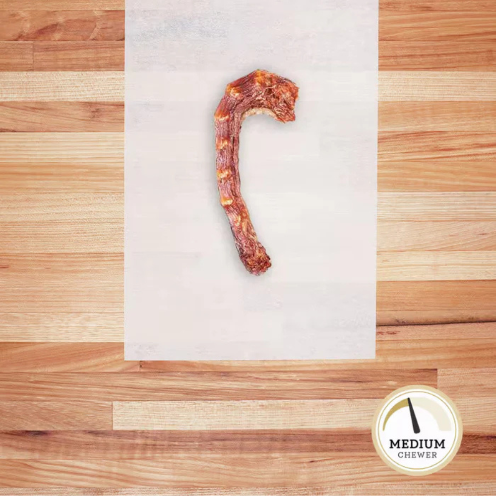 Dehydrated, skinless chicken neck on white parchment paper.