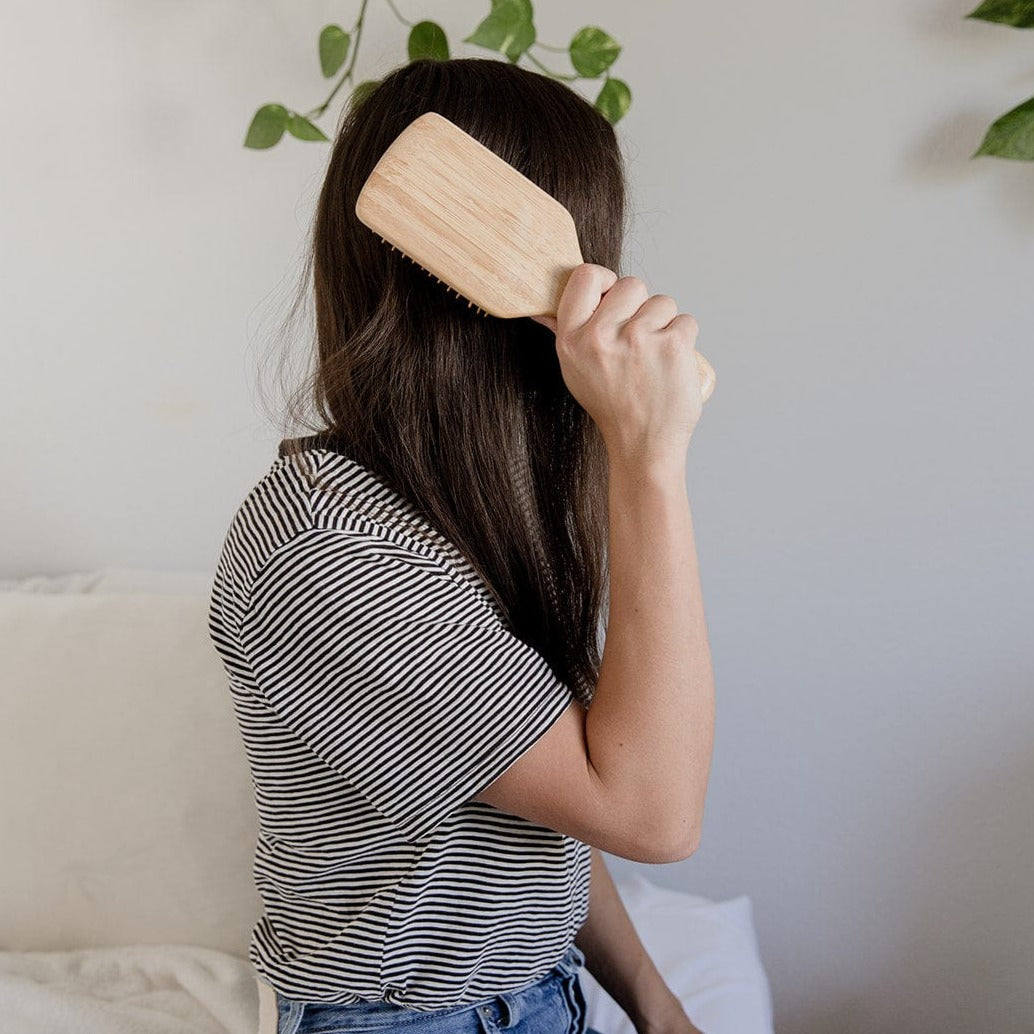 Person holding a wooden brush in front of their face with a neutral background